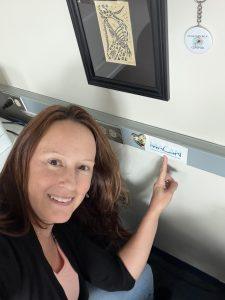 Grace Saba pointing to a MACAN sticker on a wall